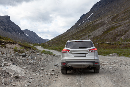 Silver suv car standing on dirt road, driving through the mountains © Kekyalyaynen