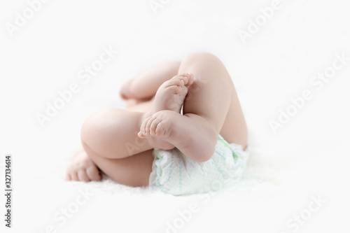 feet of a six months old baby wearing diapers lying on the bed