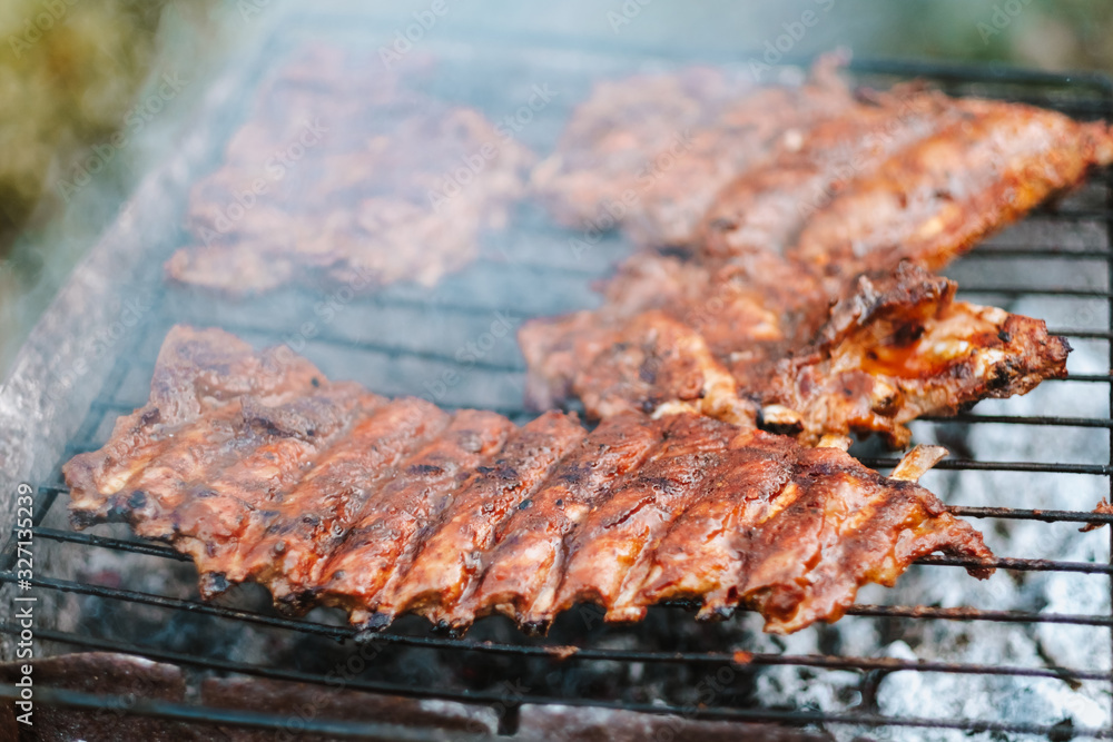 Cooking pork ribs on the grill, on an open fire, outdoors. Picnic and camping concept