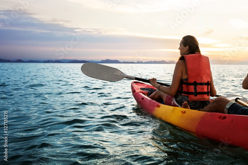 Couple kayaking together. Beautiful young couple kayaking on lake together and smiling at sunset