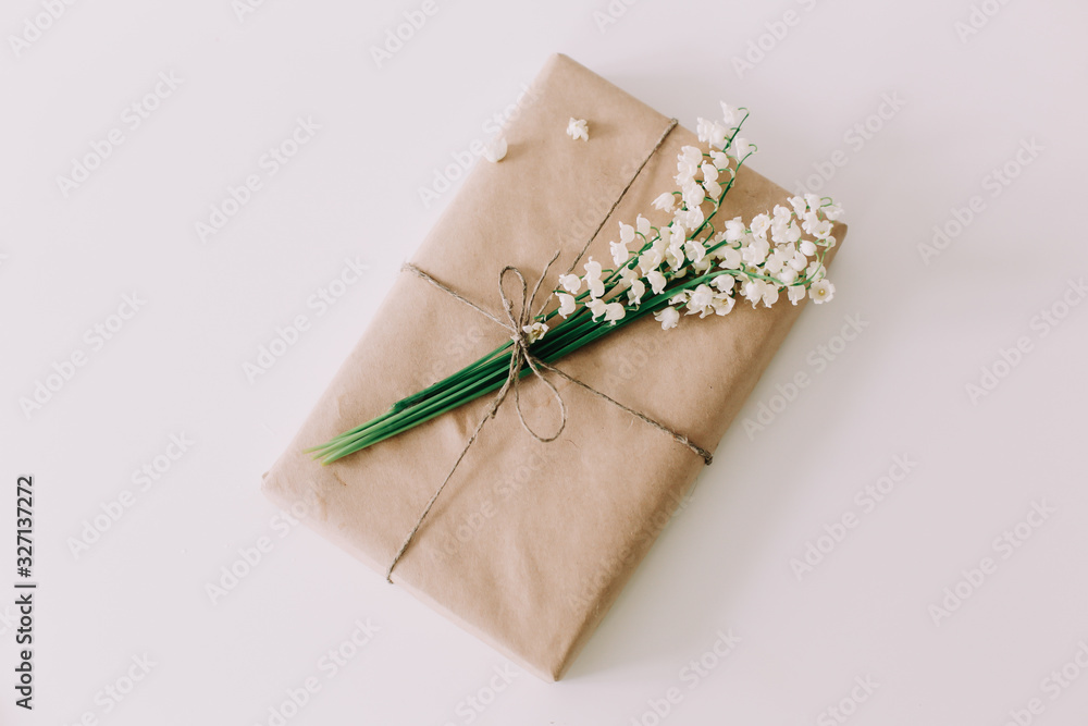 Pretty gift box with a bouquet of lilies of the valley on white background. Concept of holiday, birthday, Womens Day. flat lay Pretty gift box with a bouquet of lilies of the valley on white background. Concept of holiday, birthday, Womens Day. flat lay