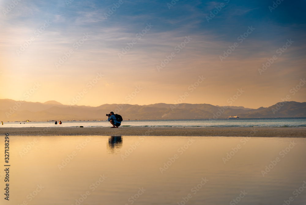 A photographer in action during the early morning walk at the shore of Boracay, Philippines A photographer in action during the early morning walk at the shore of Boracay, Philippines