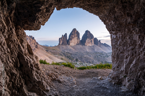 Famous mountains Three Peaks in the Dolomites from a cave during sunset
