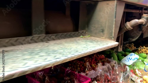 Railway train driving close to fruit and vegetable on ground in Maeklong Railway Market