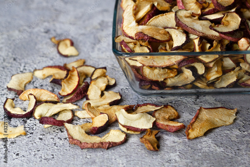 Dried Apple chips in a square glass plate on a gray concrete background. Organic natural food. side view Dried Apple chips in a square glass plate on a gray concrete background. Organic natural food. side view