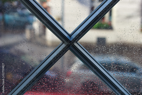 X shaped window frame with rain droplets on the glass and blurred out background