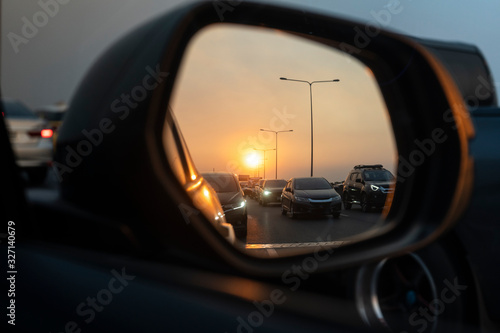 Sunset in a rear view mirror with traffic jams on expressways. sunset car driving scene.