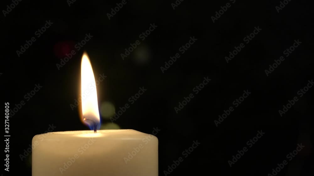 Close up of white burning candle on the table with golden light background blur Close up of white burning candle on the table with golden light background blur