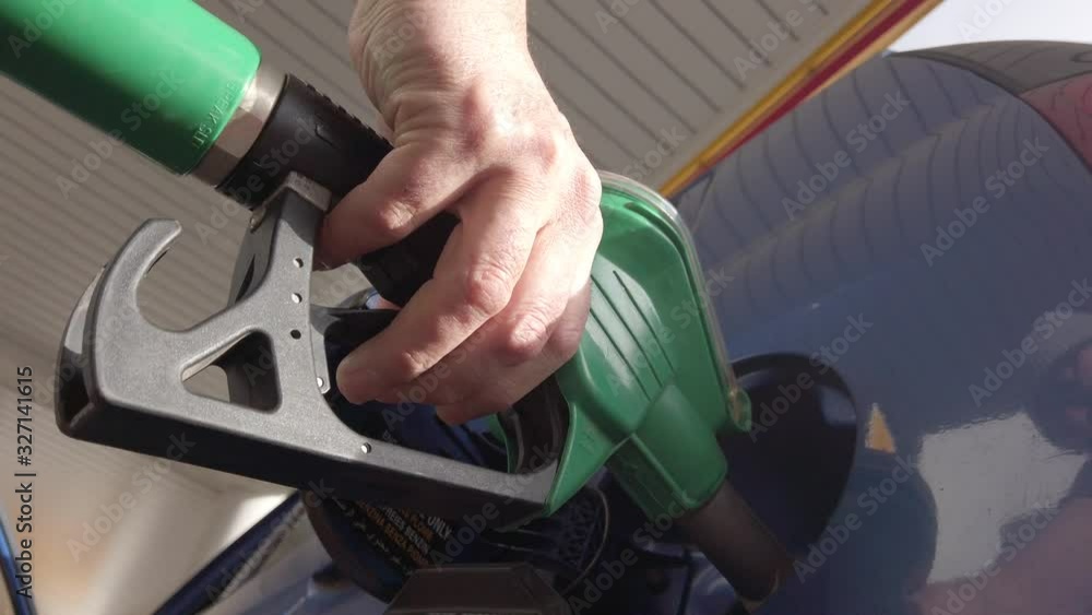 Male hand holding a gasoline nozzle in a filling station. Slow motion Male hand holding a gasoline nozzle in a filling station. Slow motion