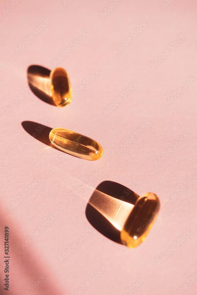 Oil yellow capsules on pink background