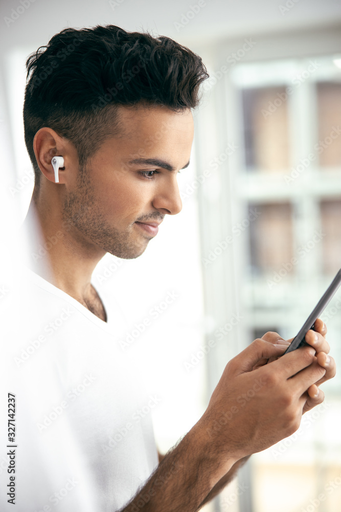 Smiling young guy using smartphone at home Smiling young guy using smartphone at home