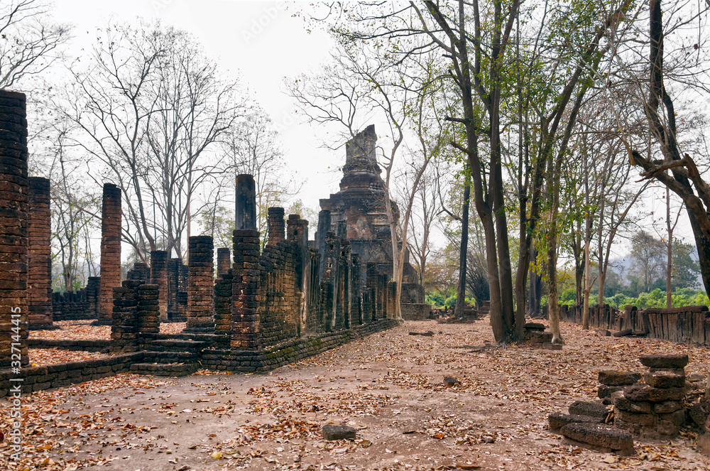 Ruins of Ancient Thai Temple (Si Satchanalai ). Trees grow between ancient stones. Si Satchanalai historical park, Northern Thailand.