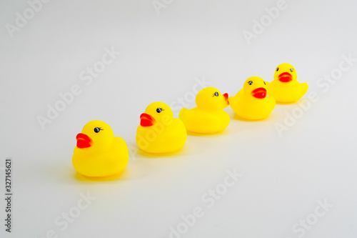 Five mini rubber ducks in a row. Two facing each other talking.