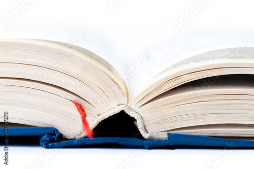 Simple opened empty light blue thick book with red tab, white background, macro, closeup, text blurred. Reading, writing, gathering knowledge, education abstract concept, light from above
