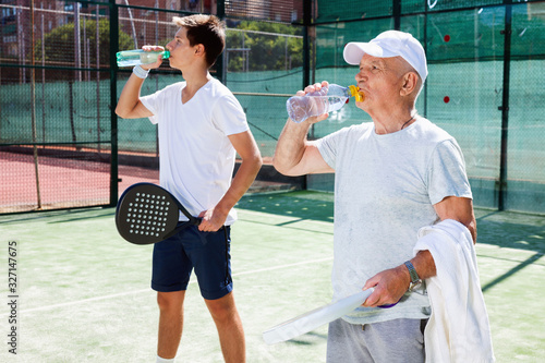 padel players of different generations drink water on padel court