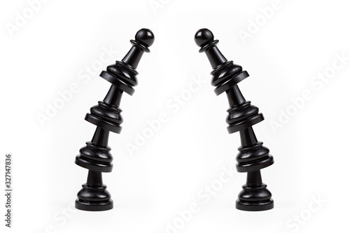 Two leaning crooked bent towers of black chess pawns forming a gate frame Passage, arch, door, border made from game pieces, copy space in the middle, on the sides Leisure, board games symbol abstract