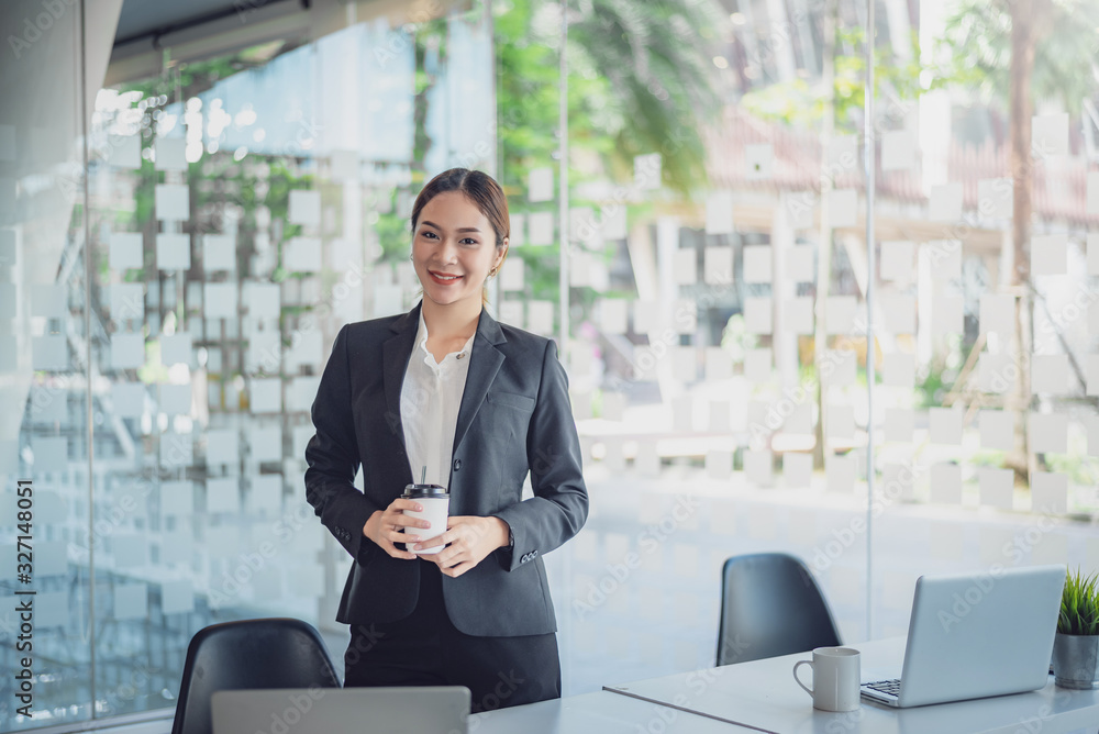 Portrait of young asian businesswoman standing holding coffee at her office looking at camera. Portrait of young asian businesswoman standing holding coffee at her office looking at camera.