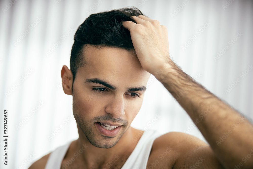 Smiling guy is combing his hair with fingers Smiling guy is combing his hair with fingers