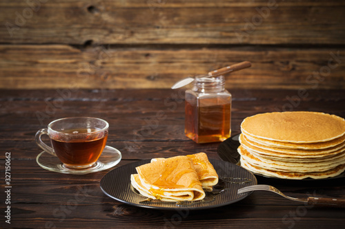 puncakes with honey and cup of tea on old wooden background photo