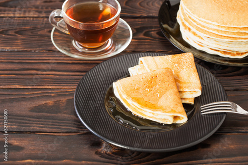 puncakes with honey and cup of tea on old wooden background photo