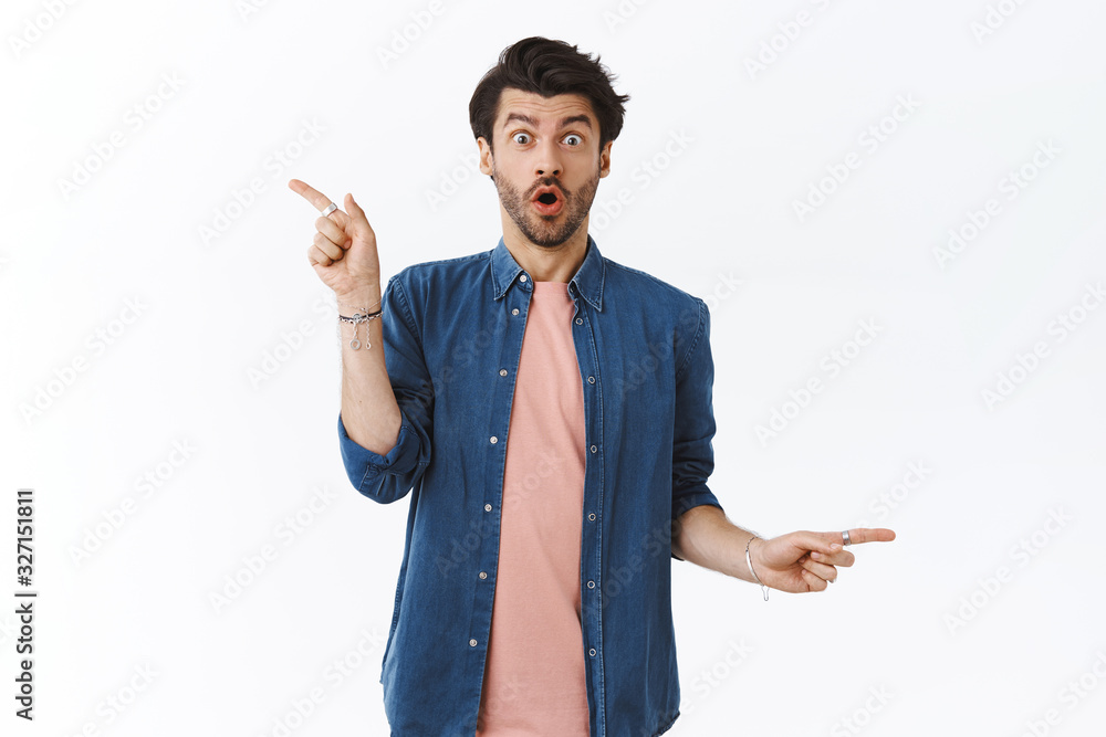 Amused, fascinated bearded hipster guy in modern outfit, gasping from amazement and surprised, pointing different sides, showing left right choices, excited so much good variants of gifts Amused, fascinated bearded hipster guy in modern outfit, gasping from amazement and surprised, pointing different sides, showing left right choices, excited so much good variants of gifts