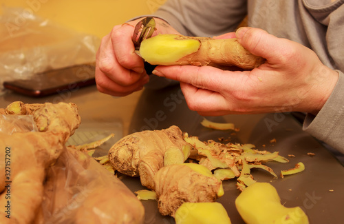 Woman (hands only) in the kitchen preparing (shaving) ginger