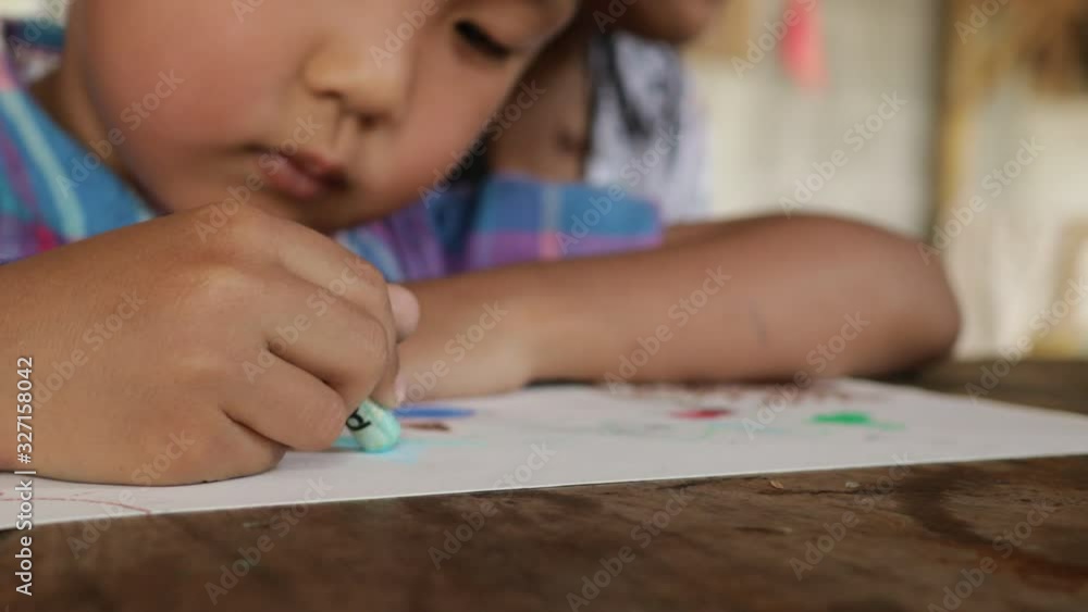 An Asian boy is drawing and coloring with fun. An Asian boy is drawing and coloring with fun.