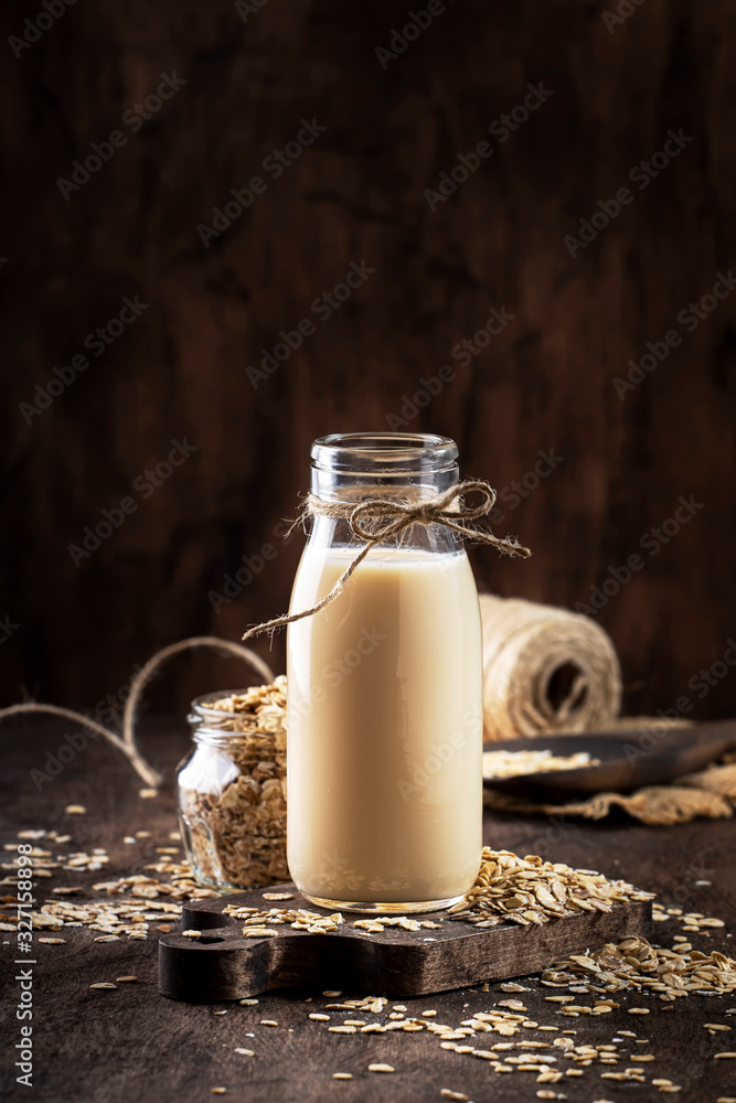 Oat flakes milk, non dairy alternative plant based drink in glass, wooden rustic kitchen table, copy space Oat flakes milk, non dairy alternative plant based drink in glass, wooden rustic kitchen table, copy space
