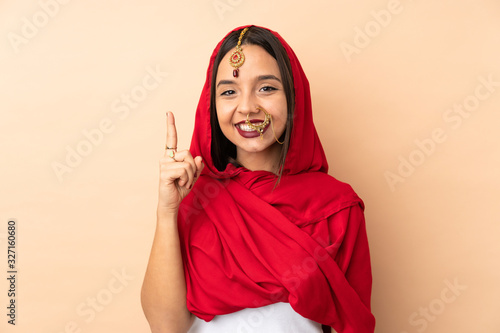 Young Indian woman isolated on beige background pointing up a great idea © luismolinero