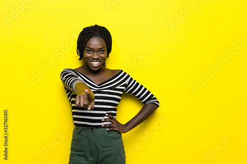 African american woman pointing on you to the camera standing over isolated yellow background © F8  \ Suport Ukraine