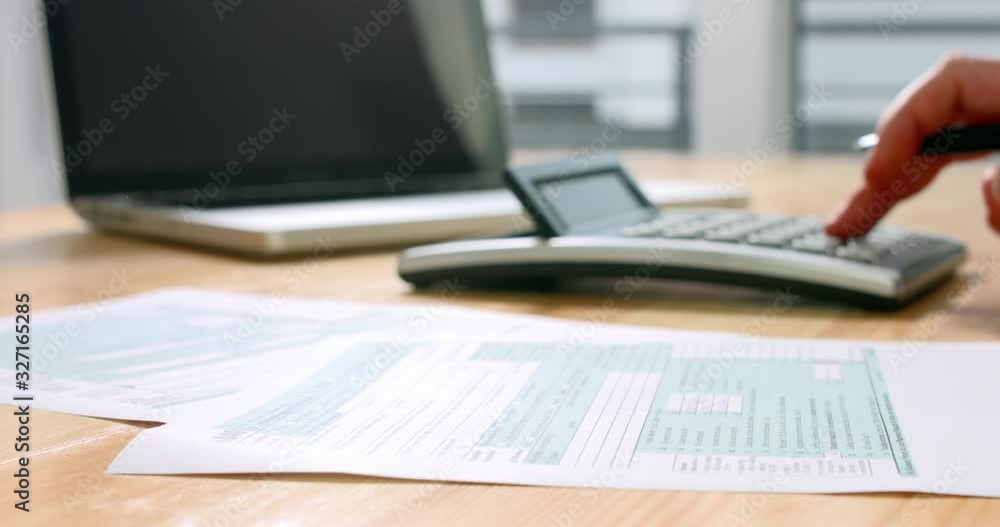 Closeup of US tax form 1040 and hand calculating and filling report paper with laptop in the office. 4k footage resolution. Closeup of US tax form 1040 and hand calculating and filling report paper with laptop in the office. 4k footage resolution.