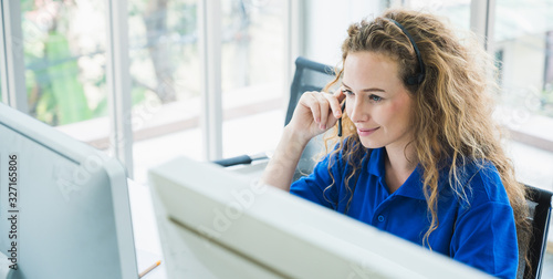 Female customer support operator at work. Team Business and Delivery call center in office. Working with a headset in blue uniform.