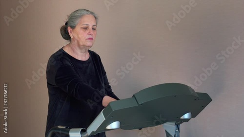 Senior white hair woman is change mode of Treadmill before training at home.