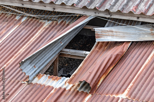 Corrugated roof with a hole. Tin plates on the roof of building.