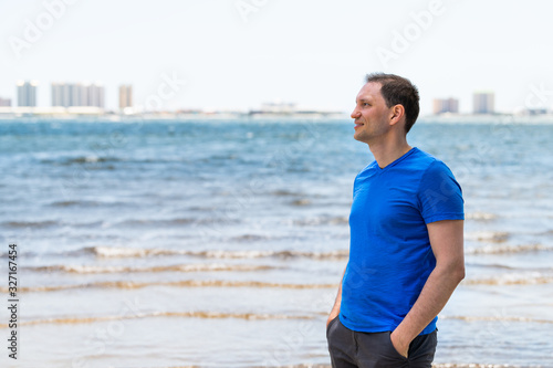 Young man on beach bay with Pensacola cityscape skyline in background in Navarre, Florida Panhandle near Gulf of Mexico