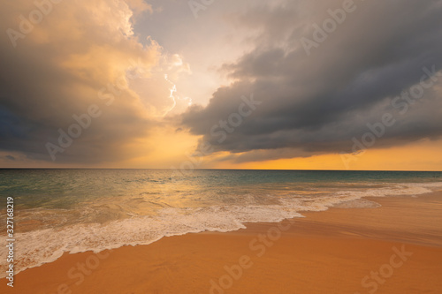 Waves on sandy ocean beach under a beautiful sunset sky with clouds on Sri Lanka island. © stone36