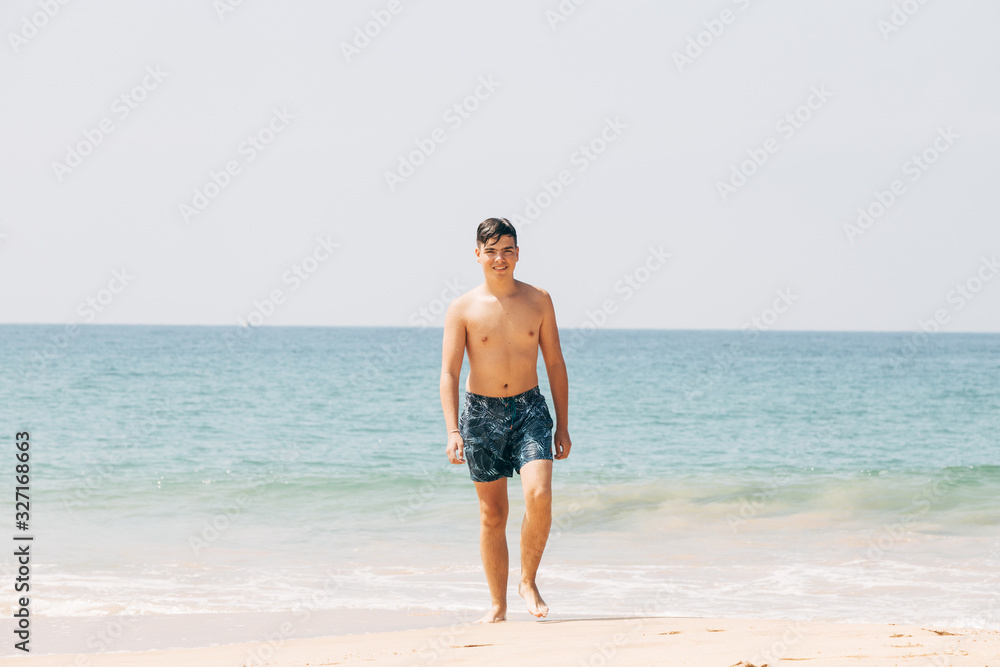 Portrait of teenage boy, coming out of the water, at the ocean sandy beach. Travel and vacation concept. Portrait of teenage boy, coming out of the water, at the ocean sandy beach. Travel and vacation concept.