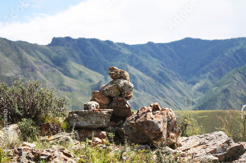 Stones are in balance. A pile of stones on a background of mountains and sky. If you stack such a pile, you will be happy. Folk omens, customs and nature. Altai.