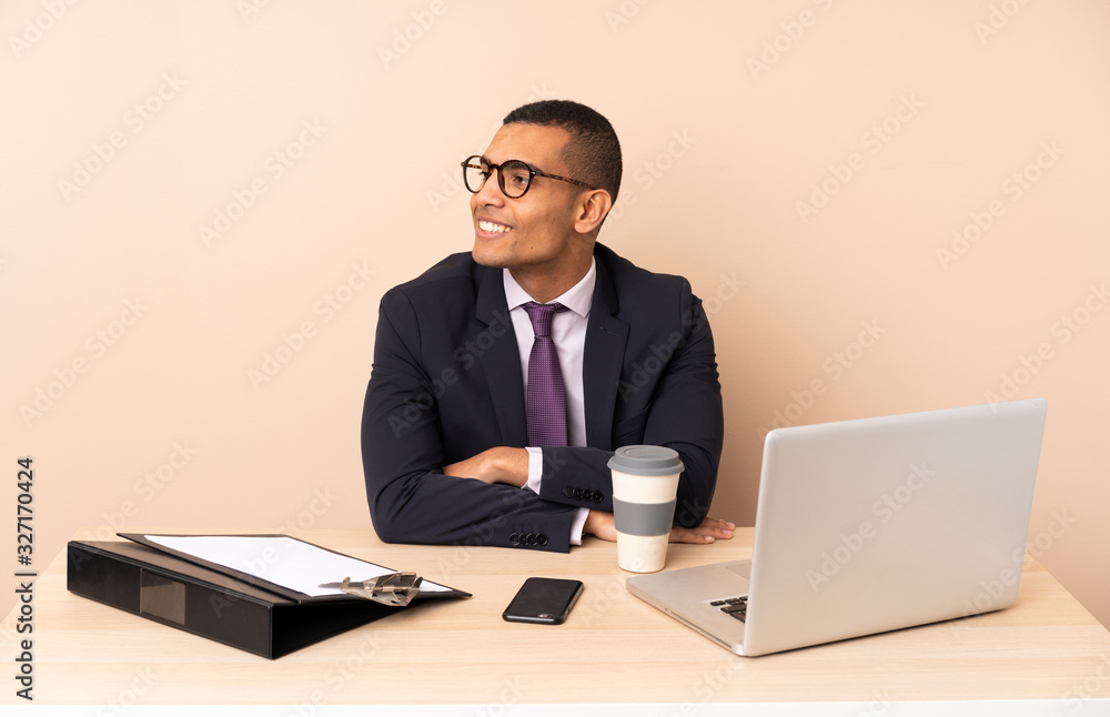 Young business man in his office with a laptop and other documents looking side Young business man in his office with a laptop and other documents looking side
