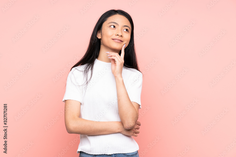 Teenager Chinese woman isolated on pink background thinking an idea while looking up Teenager Chinese woman isolated on pink background thinking an idea while looking up
