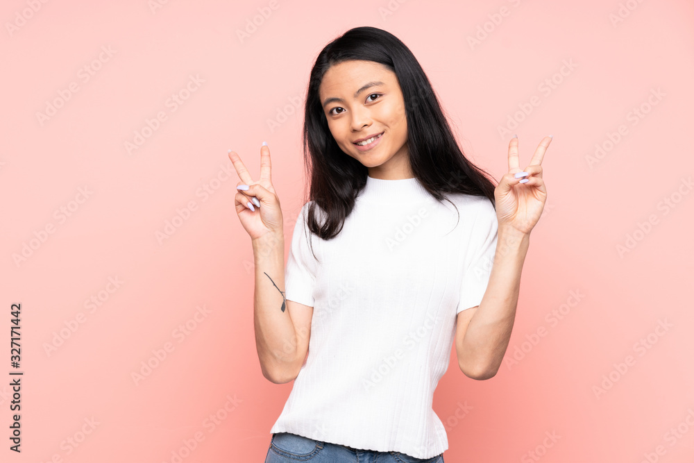 Teenager Chinese woman isolated on pink background showing victory sign with both hands Teenager Chinese woman isolated on pink background showing victory sign with both hands