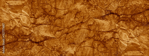 Brown orange rock background. Wide banner. Toned cracked mountains surface texture. Close-up. Stone background with copy space for design. Panoramic. 