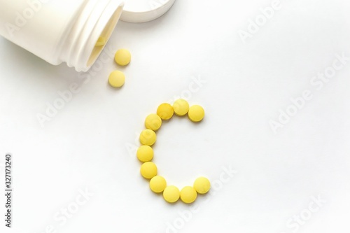 The concept of pills vitamins for treatment. Group C vitamin is laid out by yellow pills on a white isolate background. Water soluble vitamins. Lipovitamins. The complex of vitamins. Copy space.