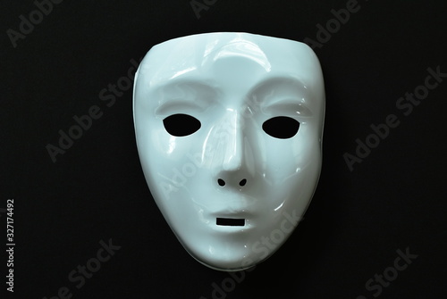 white plastic human face mask on black fabric background