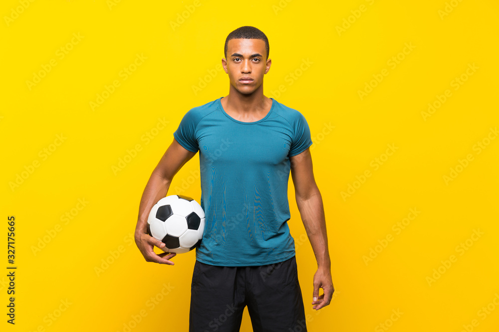 Afro American football player man over isolated yellow background Afro American football player man over isolated yellow background