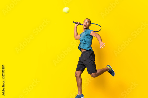 Afro American tennis player man over isolated yellow background © luismolinero