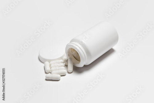 Closeup Capsules falling from white white Bottle on white background.Pills and pill Bottle Mock-up.High resolution photo.Top view