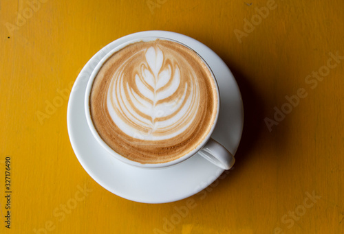 a cup of coffee on yellow background, top view