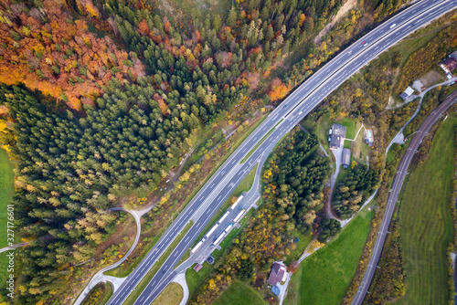 Top dawn aerial view of freeway speed road between yellow autumn forest trees in rural area.