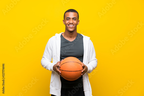 Afro American basketball player man over isolated yellow background © luismolinero